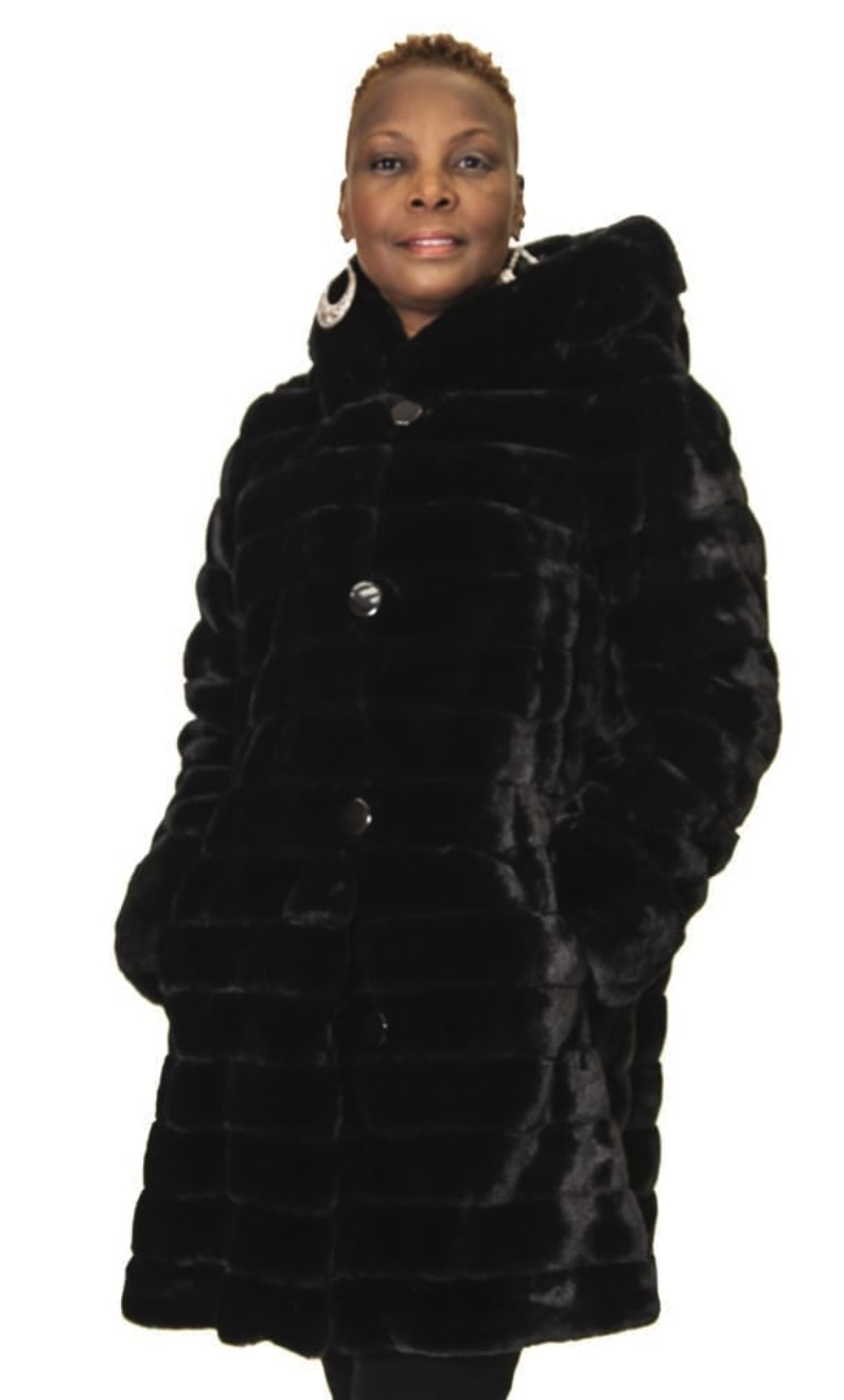 Woman wearing a long black hooded ribbed faux fur coat with silver button closures